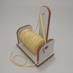 a spool of yellow thread is in a wooden holder on a white table top