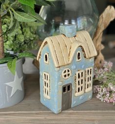 a small blue house sitting on top of a wooden table next to potted plants