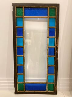 a blue and green stained glass window sitting on top of a white floor next to a wall