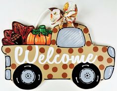 a wooden sign that says welcome with a truck and pumpkins