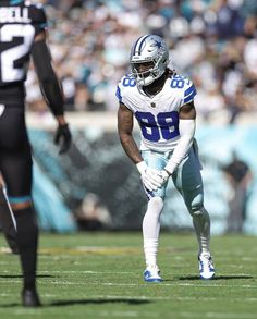 a football player standing on the field with his hands in his pockets and looking down