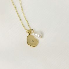 This beautiful necklace is a perfect blend of elegance and personalization. The pendant is made from gold-plated metal, giving it a stunning shimmery finish, while the shape is organic, giving it a unique and intriguing appearance.  ♡ Handcrafted and Stamped ♡ 14k Gold Plated  ♡ Natural Freshwater Pearl  ♡ Water Resistant ♡ 40cm in Photo  All of our items are carefully packed into a white jewellery box topped with a delicate white satin bow. Our shipping bags are Eco friendly, recycled, and comp Dainty Hand Stamped Necklaces For Personalized Gift, Dainty Hand Stamped Necklace For Personalized Gift, Dainty 14k Gold Filled Engraved Charm Necklaces, Everyday Yellow Gold Charm Necklace With Pearl Pendant, Dainty Pearl Pendant Necklace With Initial, Dainty Pearl Pendant Charm Necklace, Elegant Gold Hand Stamped Charm Necklaces, Elegant Gold Hand-stamped Charm Necklaces, Dainty 14k Gold Filled Hand Stamped Necklace