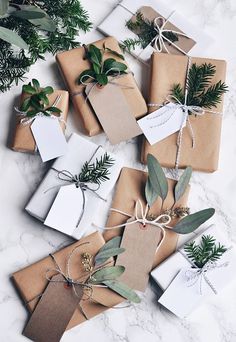 a bunch of wrapped presents sitting on top of a white marble counter with greenery