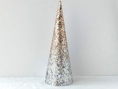 a silver glitter cone shaped vase on a white surface