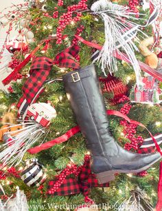 a christmas tree decorated with red, black and white plaid ribbon and boots on it