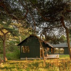 a small cabin nestled in the woods with trees around it and a picnic table on the porch