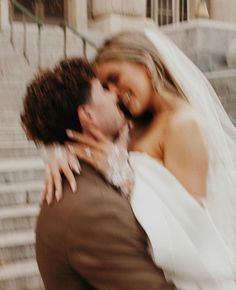 a bride and groom embracing each other in front of stairs