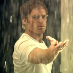 a man is holding his hands out in front of the rain coming down on him