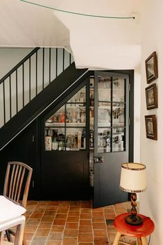 a room with a chair, table and bookshelf next to a stair case