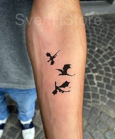 a man with a tattoo on his arm that has three bats flying in the air