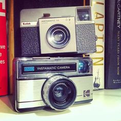 an old camera sitting on top of a book shelf next to a stack of books