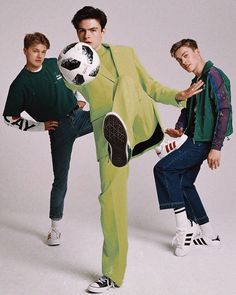 three young men in bright colored clothing are posing for a photo with a soccer ball