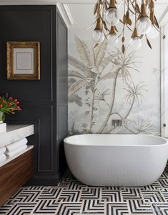 a white bath tub sitting under a chandelier in a bathroom