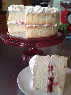 a cake with white frosting and strawberry filling on a plate next to another cake