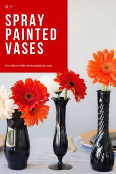 three black vases with orange and white flowers in them on a table next to plates