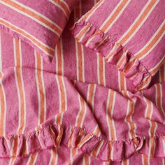 pink and orange striped bedding with ruffles on the bottom, in close up