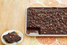 a chocolate cake sitting on top of a table next to a plate with a slice missing