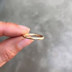 a woman's hand holding a gold wedding band