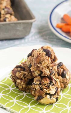 granola cookies stacked on top of each other on a plate with carrots in the background