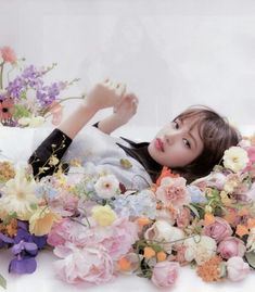 a woman laying on the ground surrounded by flowers