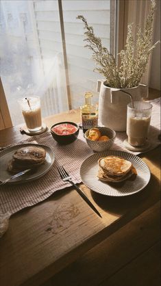 the breakfast is ready to be eaten on the table by the windowsill, with coffee and milk