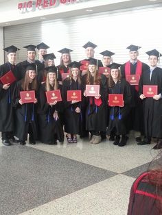 a group of people standing next to each other wearing graduation caps and gowns