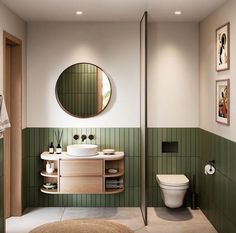 a bathroom with green tiles and white fixtures, including a round mirror above the sink