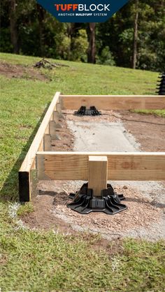 a wooden bed frame sitting on top of a lush green field