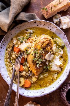 a white bowl filled with chicken and barley soup next to bread on a table top