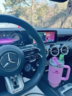 the interior of a car with steering wheel, dashboard and cup holder in front of it