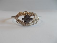 THIS IS A VERY PRETTY VINTAGE, HARLEY DAVIDSON CUFF  BRACELET. IT IS A GENUINE HARLEY ITEM. IT IS STERLING SILVER. MARKED STERLING FOR STERLING SILVER.   IT MEASURES  5 3/8" AROUND THE INSIDE, PLUS THE OPENING IS 1 1/2". SOMEWHAT ADJUSTABLE. THE FRONT MEASURES  7/8" HIGH.  IT IS IN NICE CONDITION. IT WEIGHS 16gm.  WORTHY OF BEING A GIFT.  THIS SHOP COMBINES SHIPPING. JUST PUT ALL ITEMS IN YOUR CART FIRST, THEN PAY FOR THEM. Silver Cuff Bracelet Fine Jewelry For Gift, Vintage Sterling Silver Bracelet Stamped 925, Silver Hallmarked Cuff Bracelet, Classic Silver Jewelry With Hallmark, Sterling Silver 925 Stamped Bracelet For Anniversary, Sterling Silver Cuff Bracelet For Anniversary, Custom Adjustable Sterling Silver Jewelry, Classic 925 Stamped Cuff Bracelet For Anniversary, Silver 925 Stamped Cuff Bracelet As A Gift