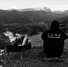 a person sitting in front of a campfire with the word sabr written on it