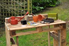 a wooden table topped with pots and gardening tools