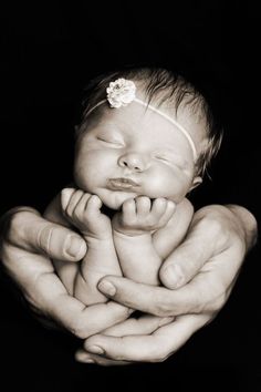 a black and white photo of a baby in its mother's arms with her hands