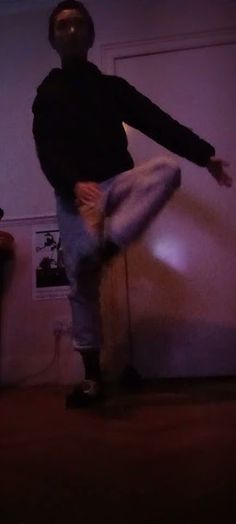 a man is standing on his skateboard in the living room at night, with one foot up