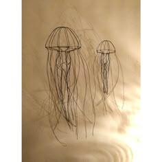 two metal jellyfish sculptures sitting next to each other on a white surface with water swirling around them