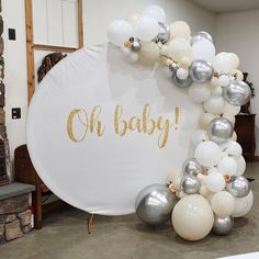 a baby shower sign surrounded by white and silver balloons