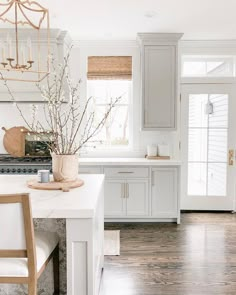 a kitchen with white cabinets and wood floors is seen in this image from the dining room