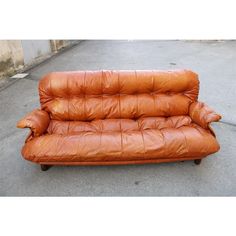 a brown leather couch sitting on top of a cement floor