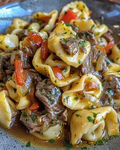 a blue plate topped with pasta covered in meat and veggies on top of sauce