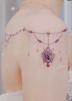 the back of a woman's shoulder is adorned with pink jewels and chains,