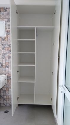 an empty white closet in a bathroom next to a sink