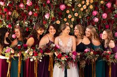 a group of women standing next to each other with flowers on the wall behind them