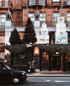 a black car driving past a tall building with christmas decorations