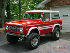 a red and white truck parked in front of a garage