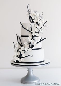 a white and black wedding cake with flowers on the top is featured in an instagram