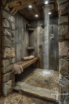 a bathroom with stone walls and a waterfall in the shower area, along with a wooden bench