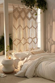 an unmade bed with white sheets and pillows in front of a curtained window