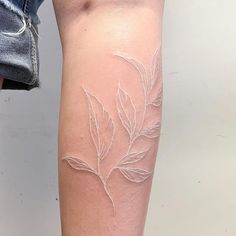 a woman's leg with a tattoo on it that has leaves painted on it