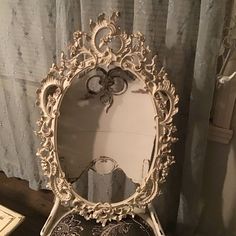 an ornately decorated vanity mirror on top of a wooden table next to a window